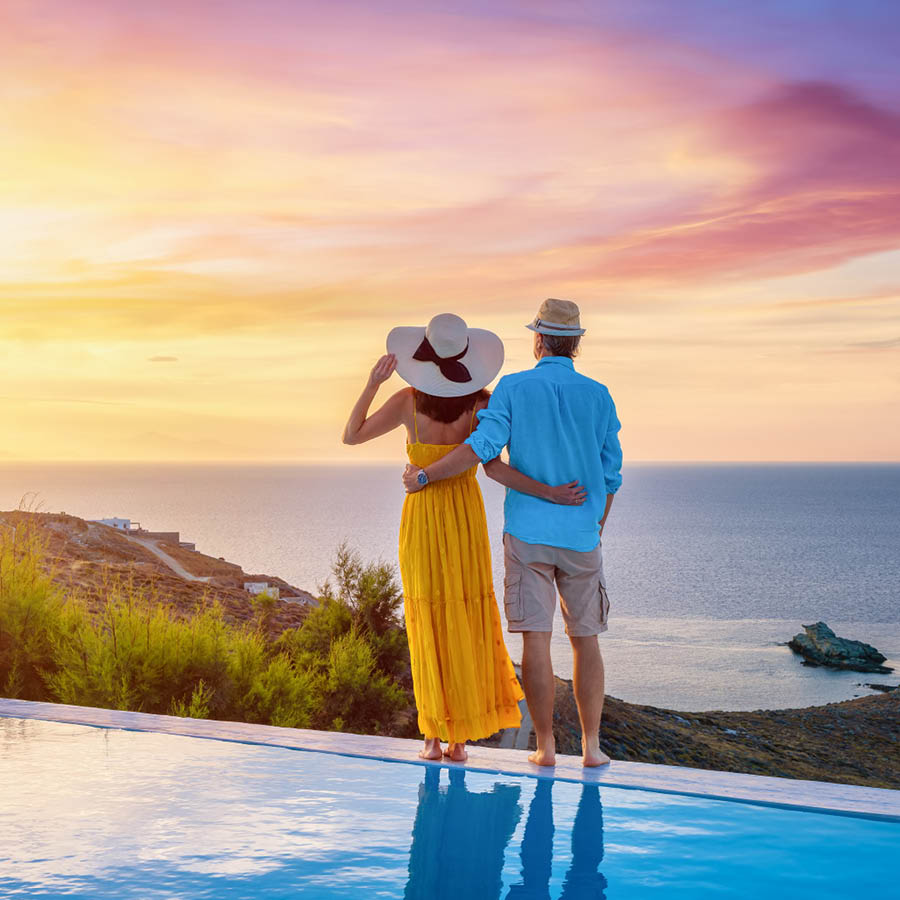 couple standing on pool edge watching sunset